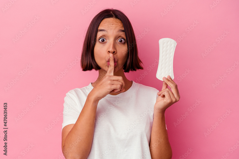 Young mixed race woman holding a compress isolated on pink background keeping a secret or asking for silence. Young mixed race woman holding a compress isolated on pink background keeping a secret or asking for silence.