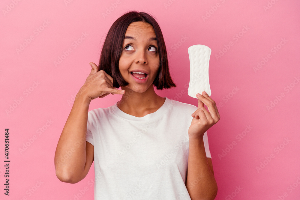 Young mixed race woman holding a compress isolated on pink background showing a mobile phone call gesture with fingers. Young mixed race woman holding a compress isolated on pink background showing a mobile phone call gesture with fingers.