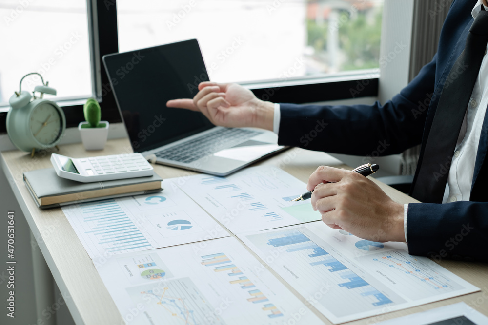 The hand of businessman sit at their desks and calculate financial graphs showing results about their investments, plan a successful business growth process The hand of businessman sit at their desks and calculate financial graphs showing results about their investments, plan a successful business growth process