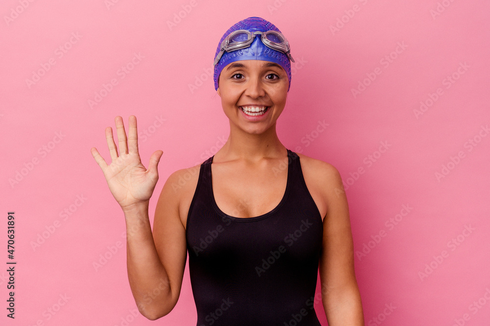 Young swimmer mixed race woman isolated on pink background smiling cheerful showing number five with fingers. Young swimmer mixed race woman isolated on pink background smiling cheerful showing number five with fingers.