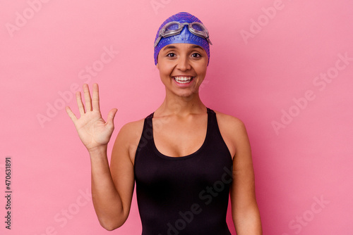 Young swimmer mixed race woman isolated on pink background smiling cheerful showing number five with fingers. © Asier