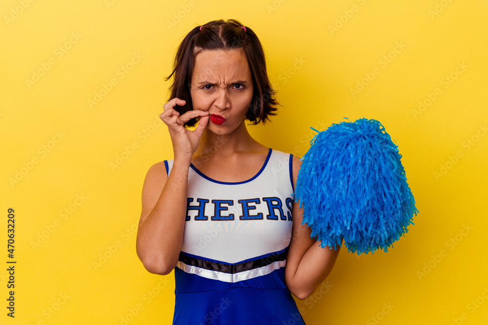 Young cheerleader mixed race woman isolated on yellow background with fingers on lips keeping a secret. Young cheerleader mixed race woman isolated on yellow background with fingers on lips keeping a secret.