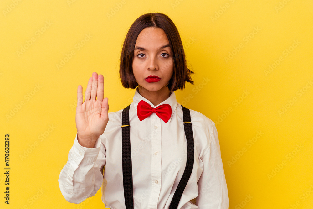 Young mixed race waitress woman isolated on yellow background standing with outstretched hand showing stop sign, preventing you. Young mixed race waitress woman isolated on yellow background standing with outstretched hand showing stop sign, preventing you.