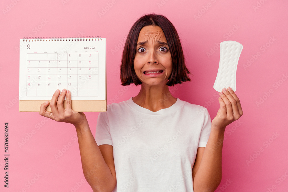Young woman holding a calendar and a menstrual pad, the period days are marked Young woman holding a calendar and a menstrual pad, the period days are marked