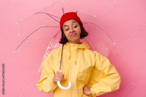 Young woman holding an umbrella expressing emotions on a pink background
