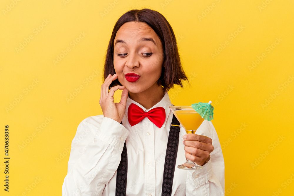 Young pretty bartender woman holding a cocktail on a yellow background Young pretty bartender woman holding a cocktail on a yellow background
