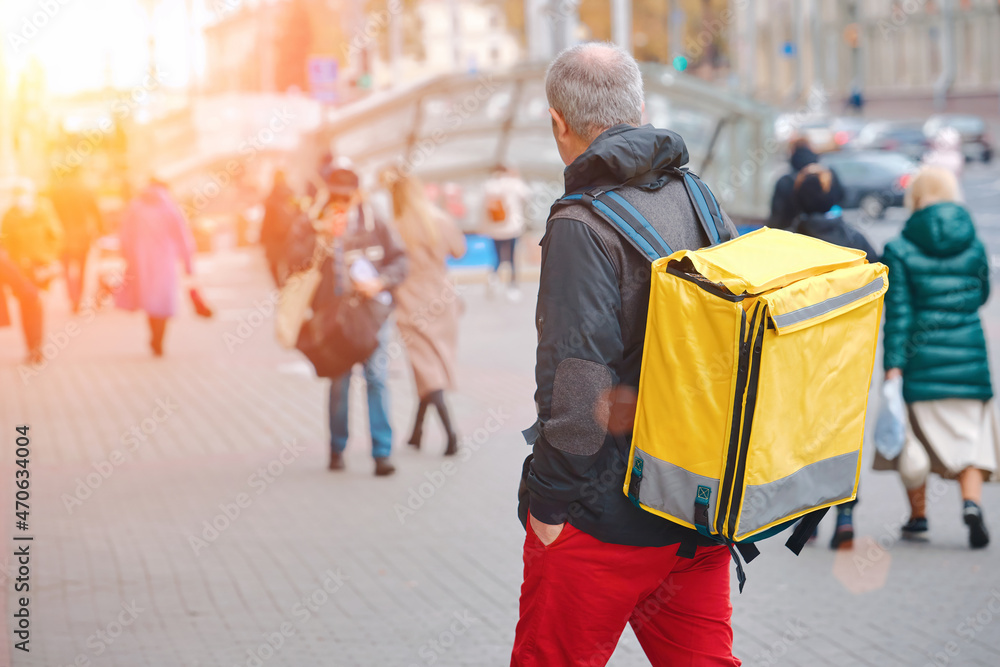 Food delivery adult courier with yellow bag delivering fast food