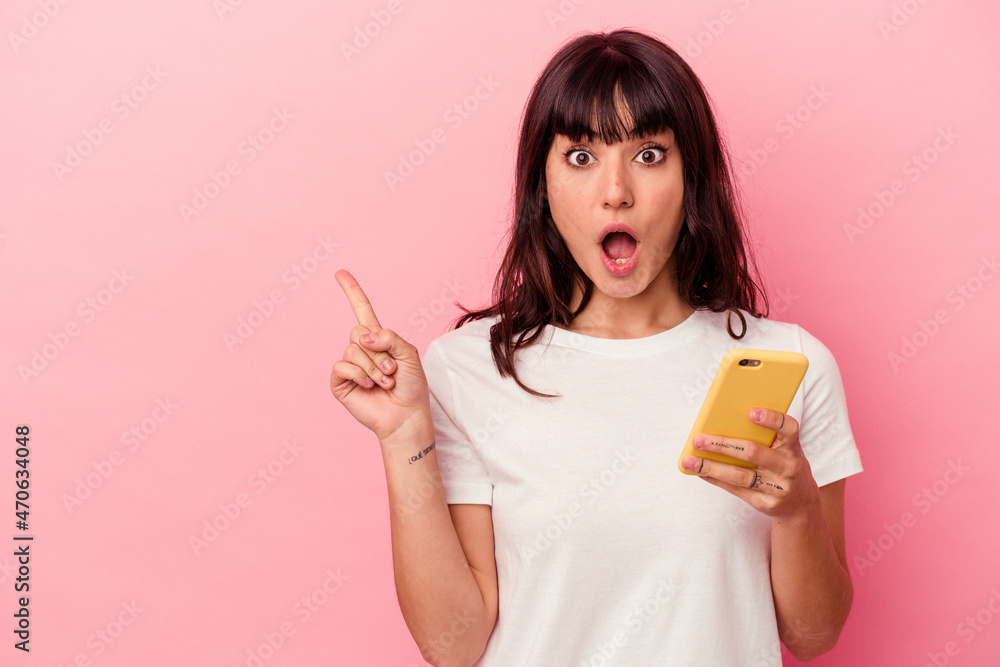 Young caucasian woman holding a mobile phone isolated on pink background pointing to the side Young caucasian woman holding a mobile phone isolated on pink background pointing to the side