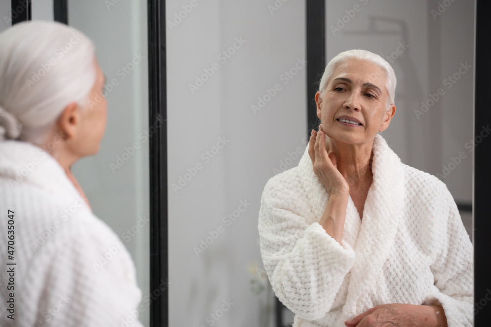 Charming elderly lady touching her glowing face Charming elderly lady touching her glowing face