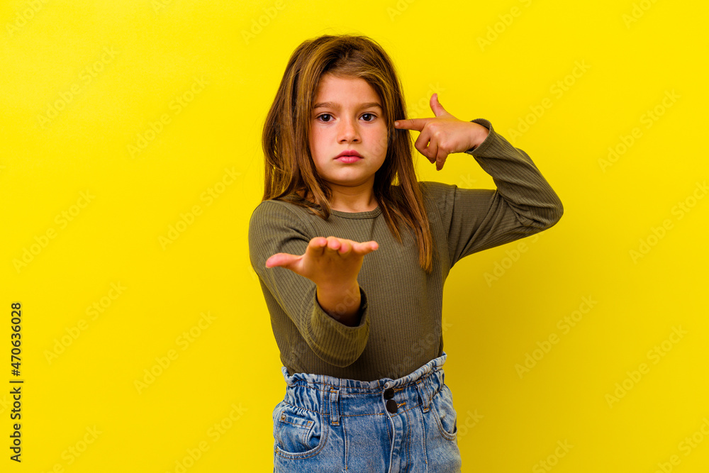 Little caucasian girl isolated on yellow background holding and showing a product on hand. Little caucasian girl isolated on yellow background holding and showing a product on hand.