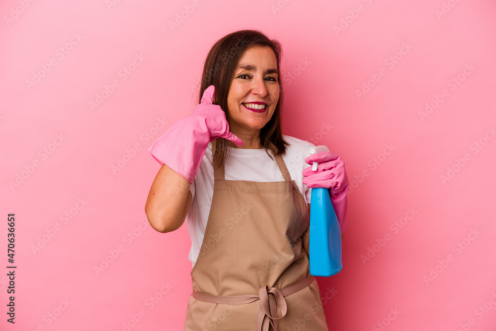 Middle age caucasian woman cleaning home isolated on pink background showing a mobile phone call gesture with fingers. Middle age caucasian woman cleaning home isolated on pink background showing a mobile phone call gesture with fingers.