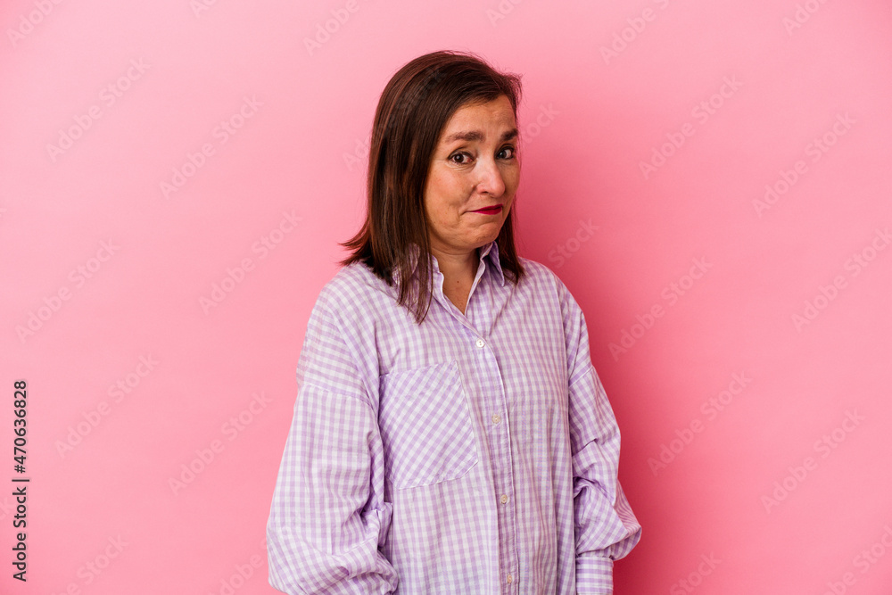 Obraz premium Middle age caucasian woman isolated on pink background shrugs shoulders and open eyes confused.
