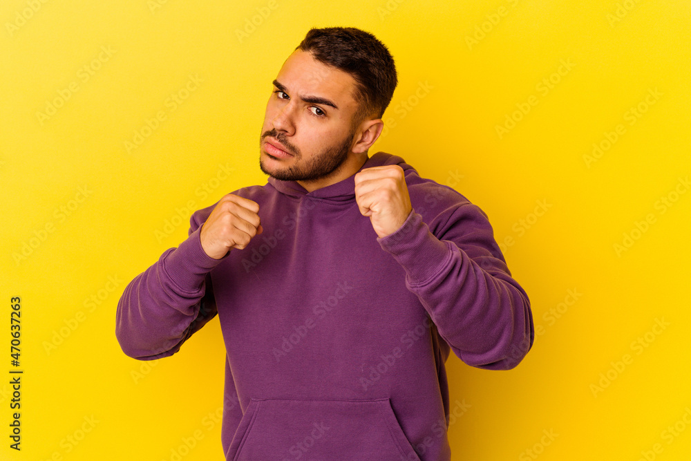 Young caucasian man isolated on yellow background throwing a punch, anger, fighting due to an argument, boxing. Young caucasian man isolated on yellow background throwing a punch, anger, fighting due to an argument, boxing.