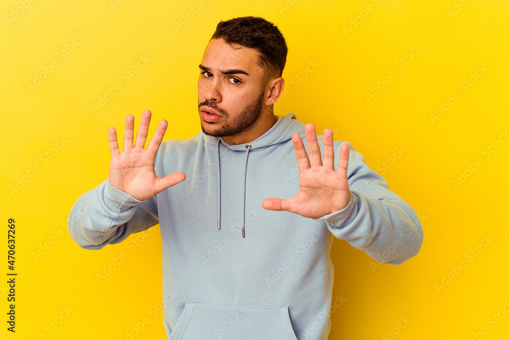 Young caucasian man isolated on yellow background rejecting someone showing a gesture of disgust. Young caucasian man isolated on yellow background rejecting someone showing a gesture of disgust.