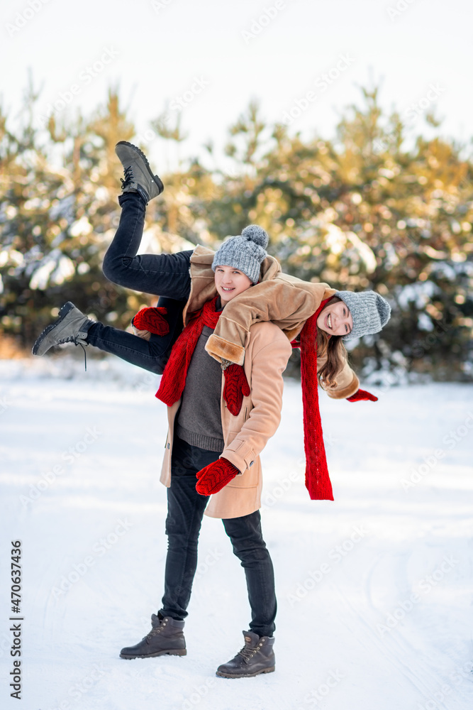 Handsome guy carrying laughing girlfriend on his shoulder, winter shot Handsome guy carrying laughing girlfriend on his shoulder, winter shot