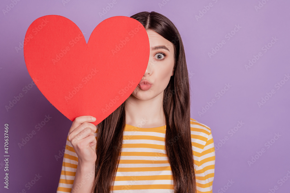 Portrait of romantic cupid lady hold red paper heart hide eye send air kiss on violet background Portrait of romantic cupid lady hold red paper heart hide eye send air kiss on violet background