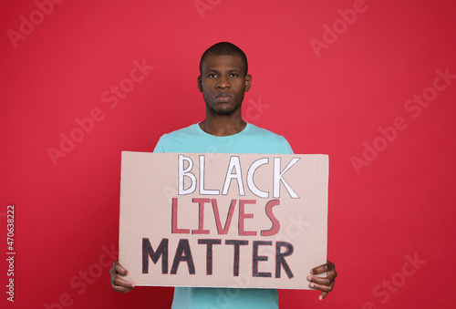 African American man holding sign with phrase Black Lives Matter on red background. End racism photo