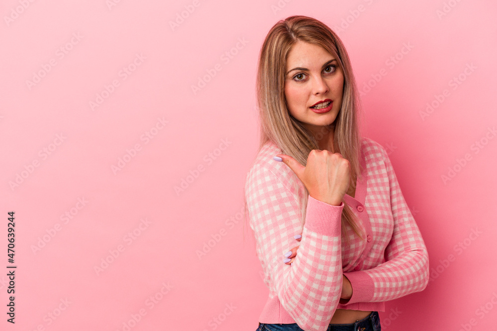 Young russian woman isolated on pink background points with thumb finger away, laughing and carefree. Young russian woman isolated on pink background points with thumb finger away, laughing and carefree.