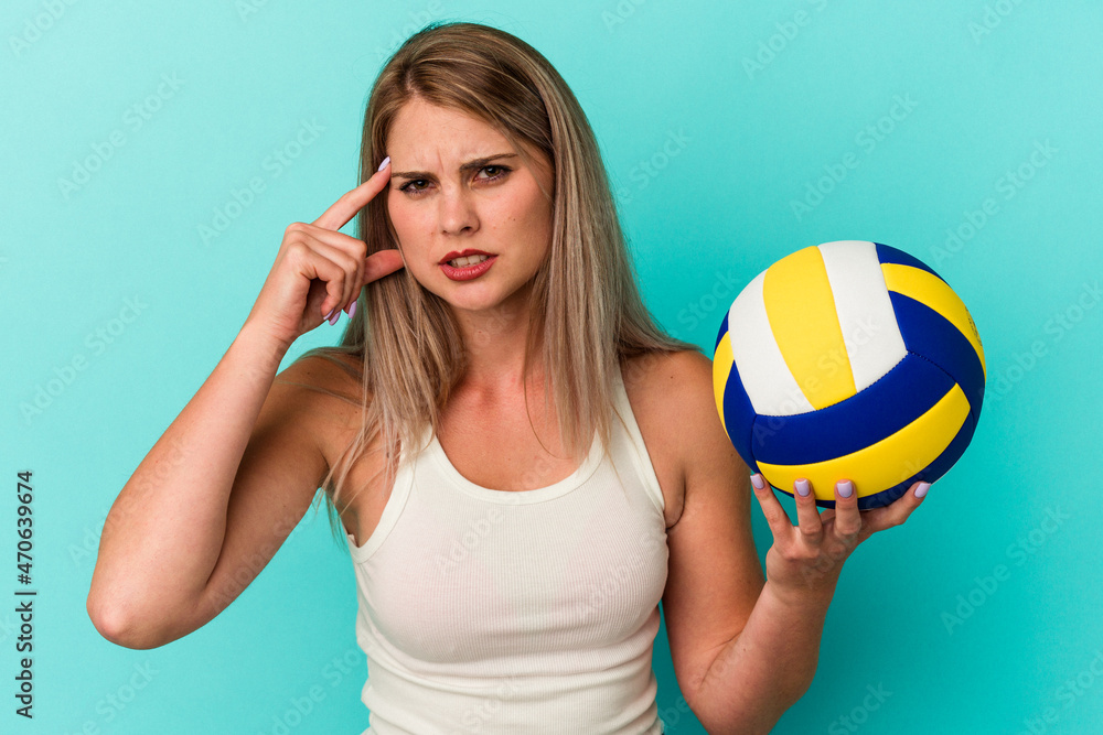 Young russian woman playing volleyball isolated on blue background showing a disappointment gesture with forefinger.