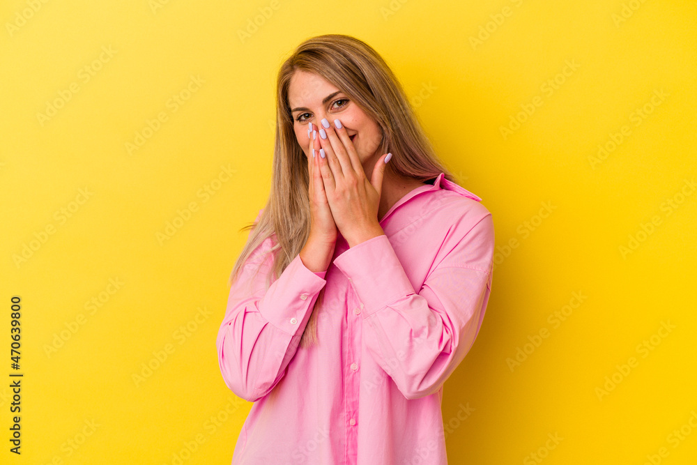 Young russian woman isolated on yellow background laughing about something, covering mouth with hands. Young russian woman isolated on yellow background laughing about something, covering mouth with hands.