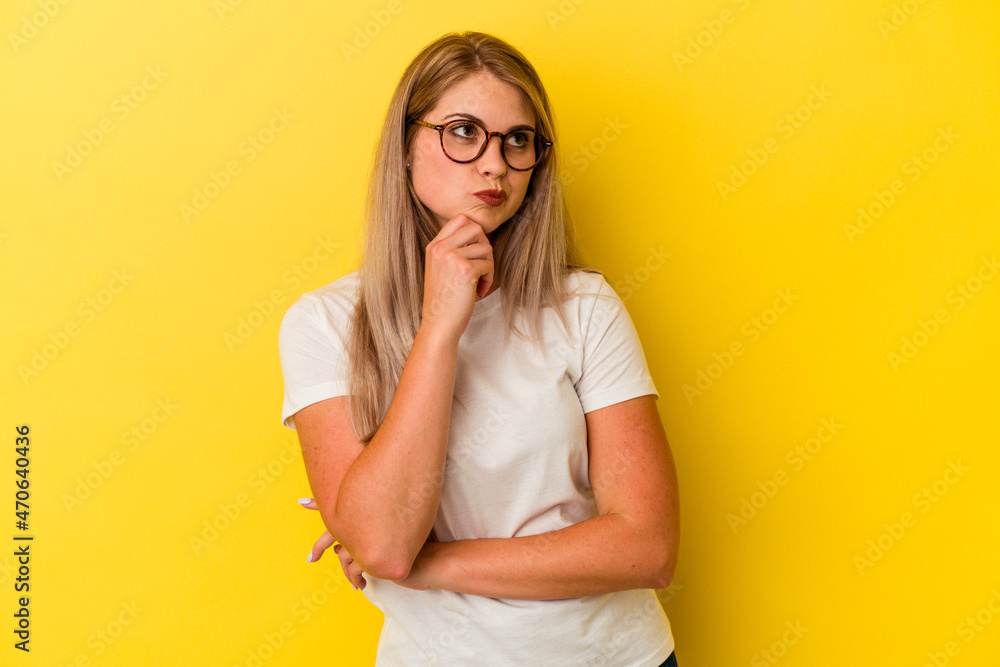 Young russian woman isolated on yellow background thinking and looking up, being reflective, contemplating, having a fantasy. Young russian woman isolated on yellow background thinking and looking up, being reflective, contemplating, having a fantasy.