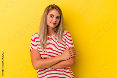 Young russian woman isolated on yellow background who feels confident, crossing arms with determination.