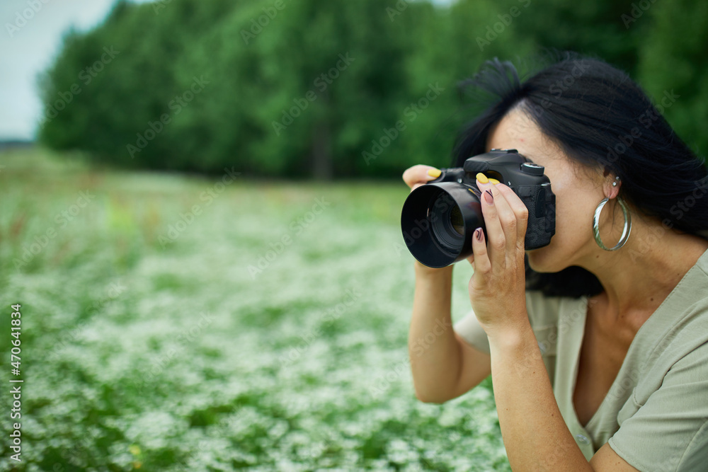 Portrait of Female photographer take photo outdoors on flower field landscape holding a camera Portrait of Female photographer take photo outdoors on flower field landscape holding a camera