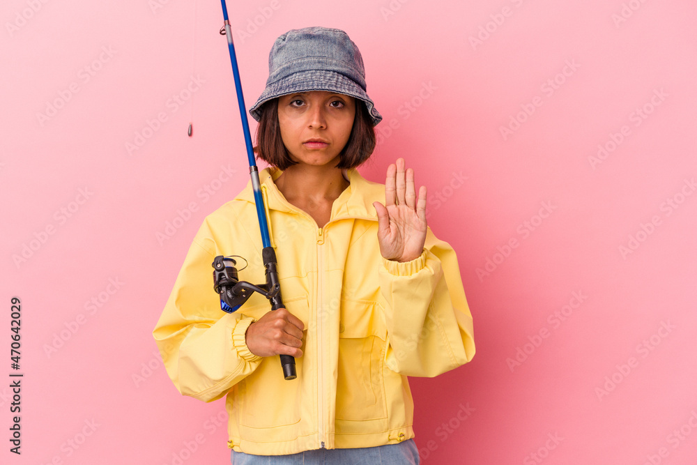 Young mixed race woman practicing fishing isolated on pink background standing with outstretched hand showing stop sign, preventing you. Young mixed race woman practicing fishing isolated on pink background standing with outstretched hand showing stop sign, preventing you.