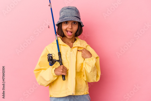 Young mixed race woman practicing fishing isolated on pink background person pointing by hand to a shirt copy space, proud and confident
