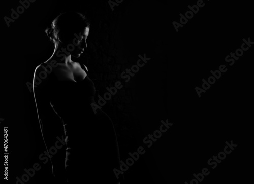 Silhouette profile of a young beautiful woman on a dark background. Place for text about beauty and health.