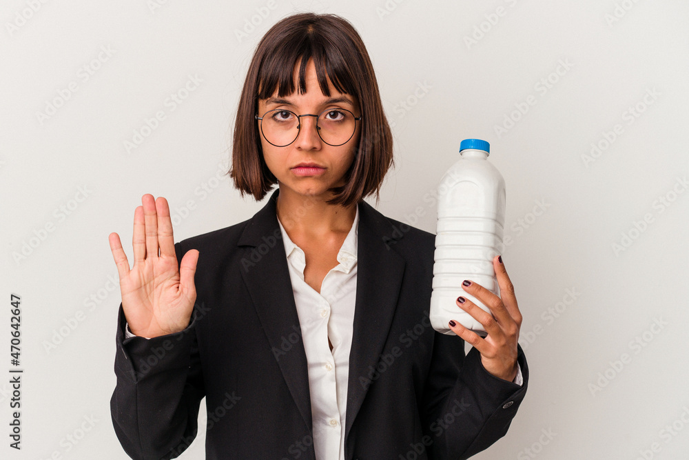 Young mixed race business woman holding a milk bottle isolated on white background standing with outstretched hand showing stop sign, preventing you. Young mixed race business woman holding a milk bottle isolated on white background standing with outstretched hand showing stop sign, preventing you.