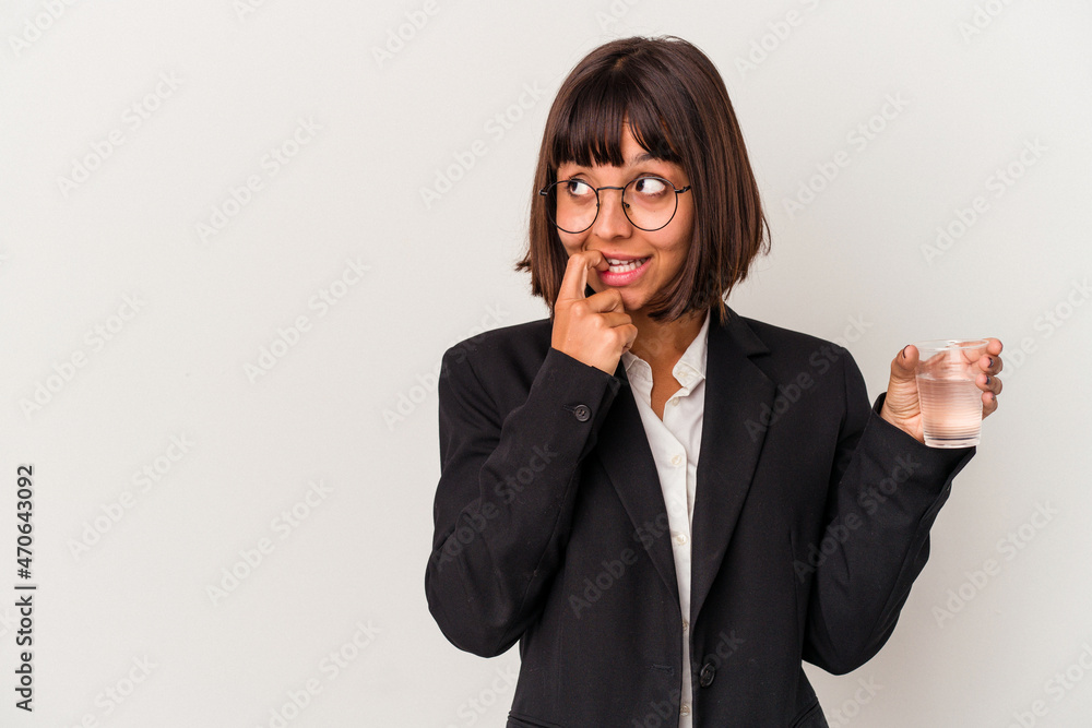 Young mixed race business woman holding a glass of water isolated on white background relaxed thinking about something looking at a copy space. Young mixed race business woman holding a glass of water isolated on white background relaxed thinking about something looking at a copy space.