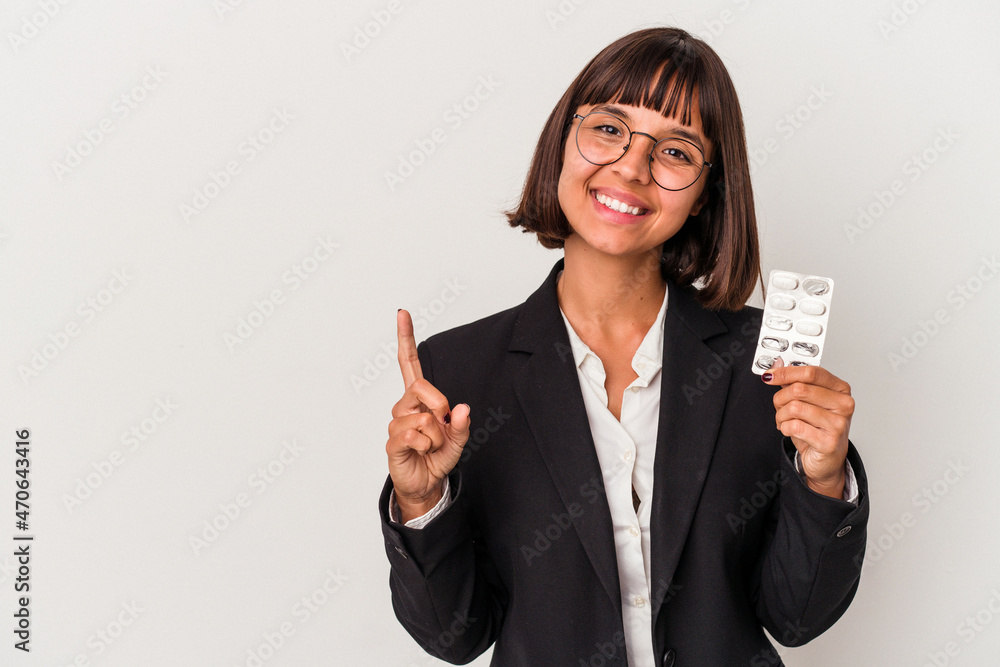 Young mixed race business woman holding pills isolated showing number one with finger. Young mixed race business woman holding pills isolated showing number one with finger.