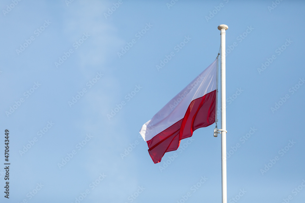 The national flag of Poland flies against a blue sky and a few white clouds. The national flag of Poland flies against a blue sky and a few white clouds.