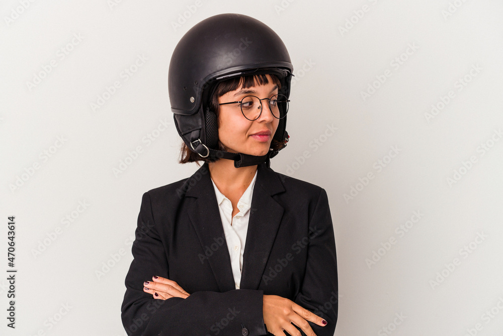 Young mixed race business woman wearing a motorbike helmet isolated looks aside smiling, cheerful and pleasant. Young mixed race business woman wearing a motorbike helmet isolated looks aside smiling, cheerful and pleasant.