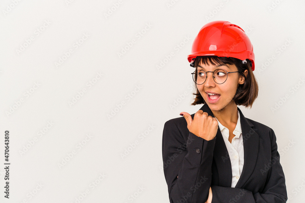 Young architect woman with red helmet isolated on white background points with thumb finger away, laughing and carefree. Young architect woman with red helmet isolated on white background points with thumb finger away, laughing and carefree.