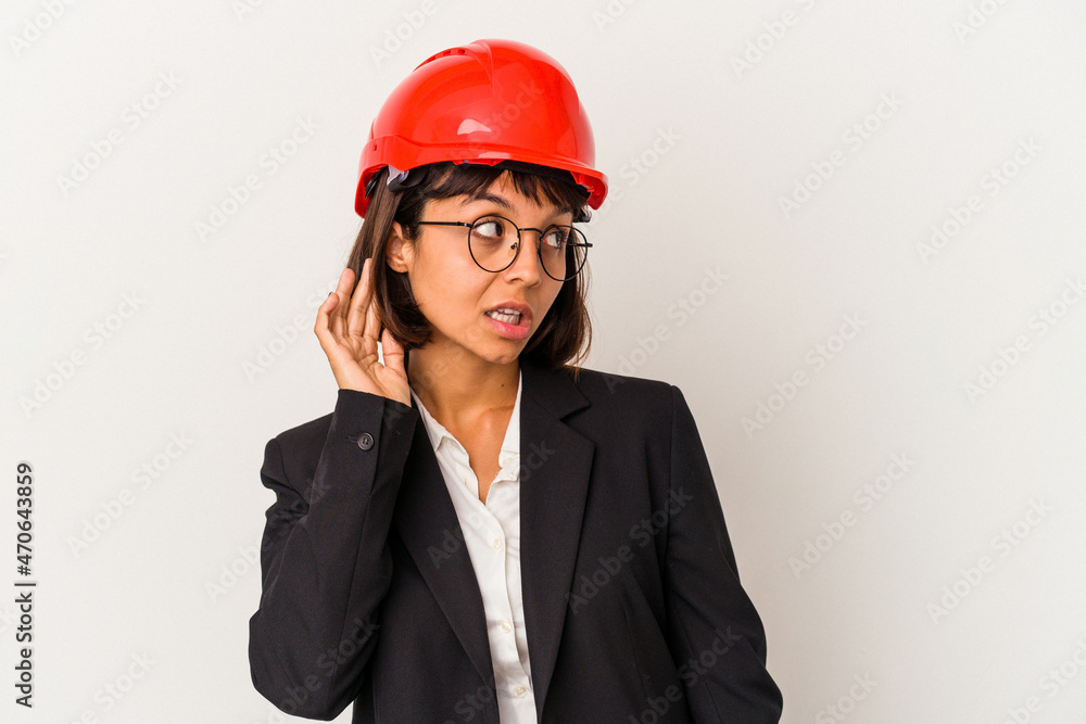Young architect woman with red helmet isolated on white background trying to listening a gossip. Young architect woman with red helmet isolated on white background trying to listening a gossip.