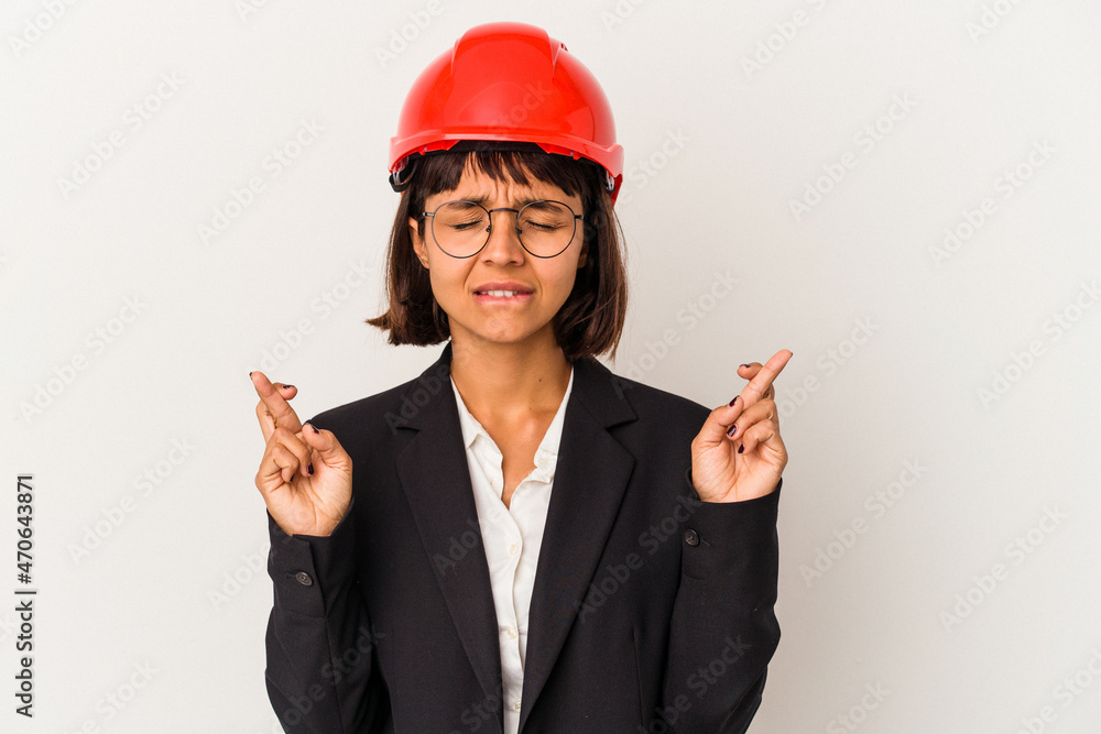 Young architect woman with red helmet isolated on white background crossing fingers for having luck Young architect woman with red helmet isolated on white background crossing fingers for having luck