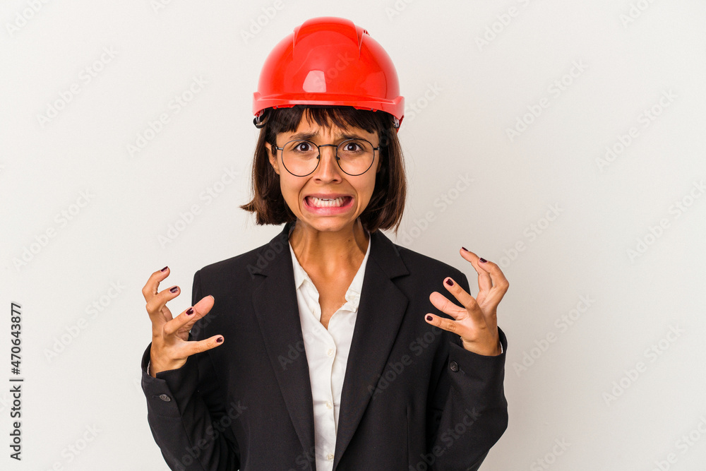 Young architect woman with red helmet isolated on white background screaming with rage. Young architect woman with red helmet isolated on white background screaming with rage.