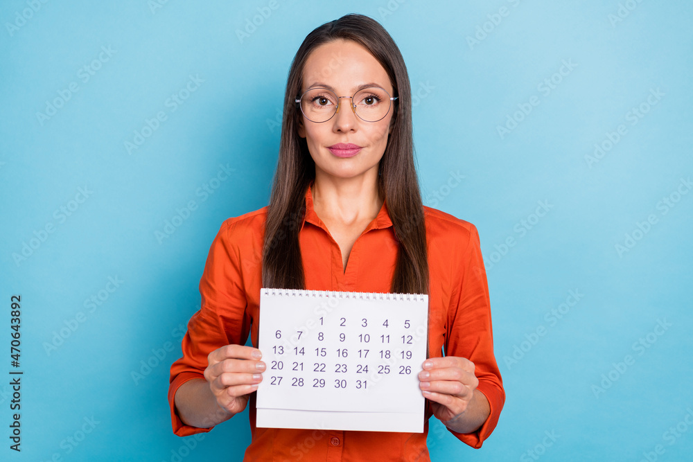 Photo of serious confident mature lady dressed red shirt glasses holding calendar isolated blue color background Photo of serious confident mature lady dressed red shirt glasses holding calendar isolated blue color background