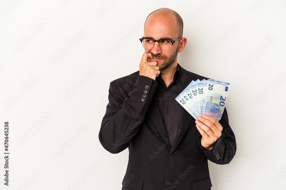 Young business bald man holding bills isolated on white background relaxed thinking about something looking at a copy space. Young business bald man holding bills isolated on white background relaxed thinking about something looking at a copy space.