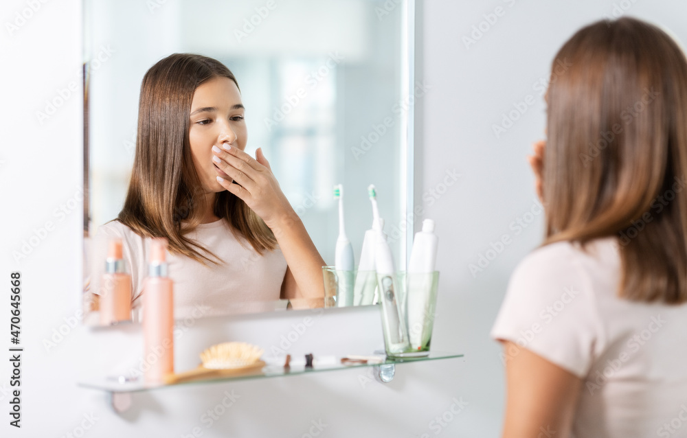 beauty, morning and people concept - teenage girl yawning in front of mirror at bathroom