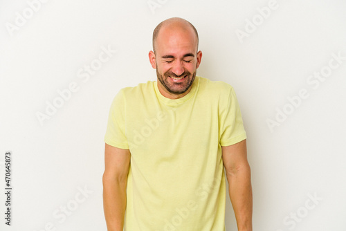 Young bald man isolated on white background laughs and closes eyes, feels relaxed and happy.