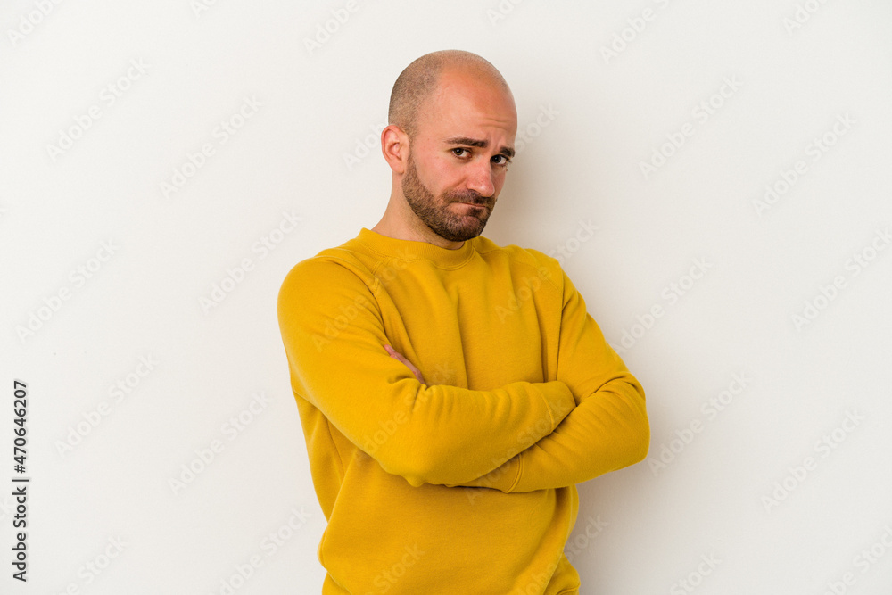 Young bald man isolated on white background suspicious, uncertain, examining you.