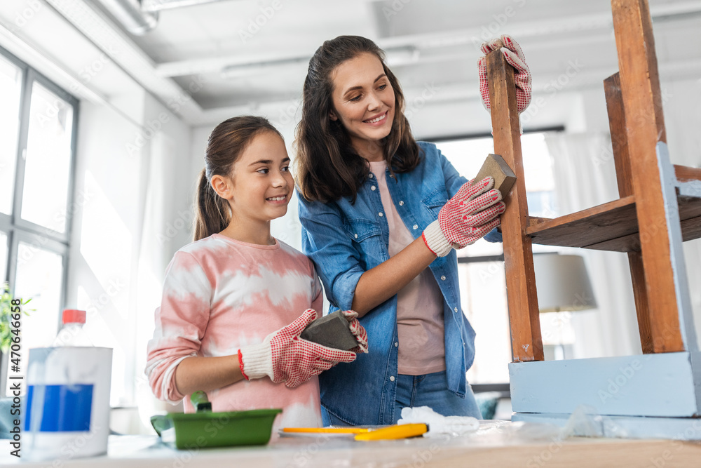 furniture renovation, diy and home improvement concept - happy smiling mother and daughter sanding old round wooden table with sponge at home furniture renovation, diy and home improvement concept - happy smiling mother and daughter sanding old round wooden table with sponge at home