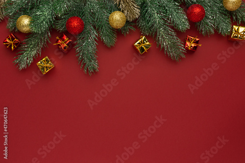 Christmas composition. Coniferous branches and decorative ornaments on a red background.