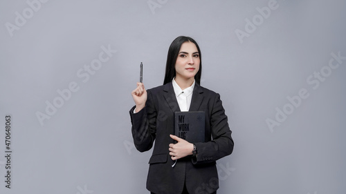 young businesswomen looking front  holding pen and book  wearing black coat indian pakistani model photo