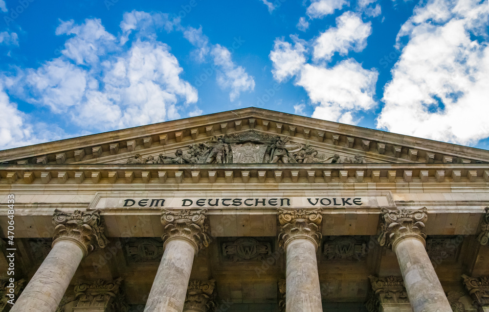 Fototapeta premium Great low-angle view of the inscription Dem Deutschen Volke, meaning To the German people, on the frieze between the columns and the pediment of the Reichstag building in Berlin, Germany.