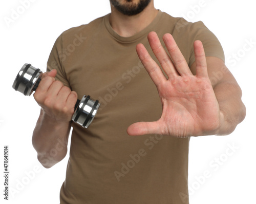 Sporty man with dumbbell suffering from calluses on hands against white background, closeup