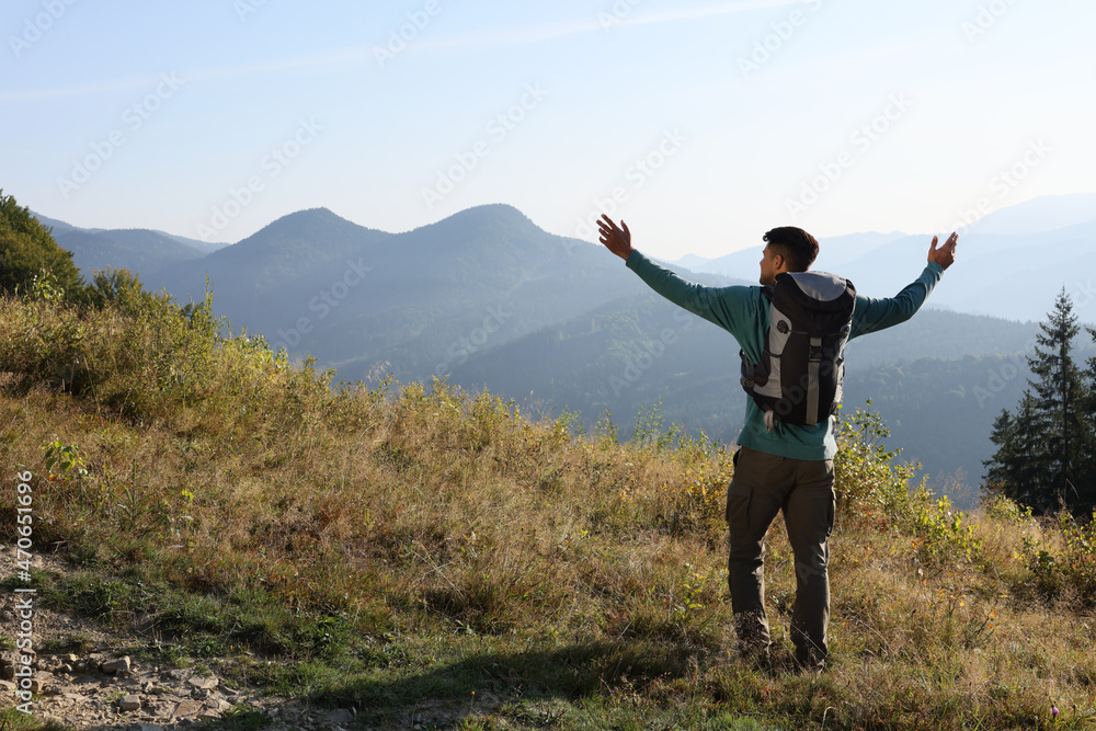 Tourist with backpack in mountains on sunny day, back view. Space for text Tourist with backpack in mountains on sunny day, back view. Space for text